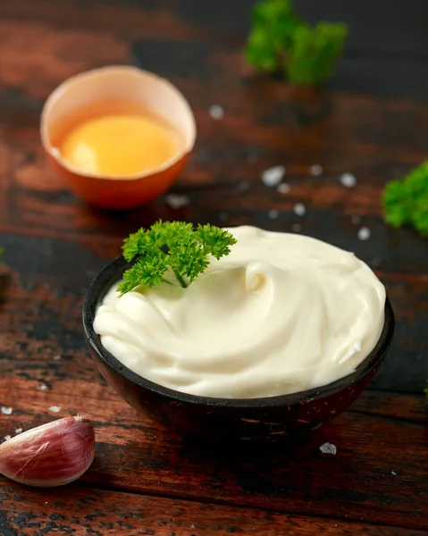 Mayonnaise sauce in a wooden bowl with egg, mustard, garlic and herbs — Stockfoto