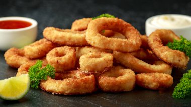 Fırında pişirilmiş kalamar halkaları limon dilimleri, acı biber sosu ve mayonez ile servis edilir.