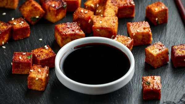 Tofu frito com pauzinho e sementes de gergelim em tábua de pedra rústica — Fotografia de Stock