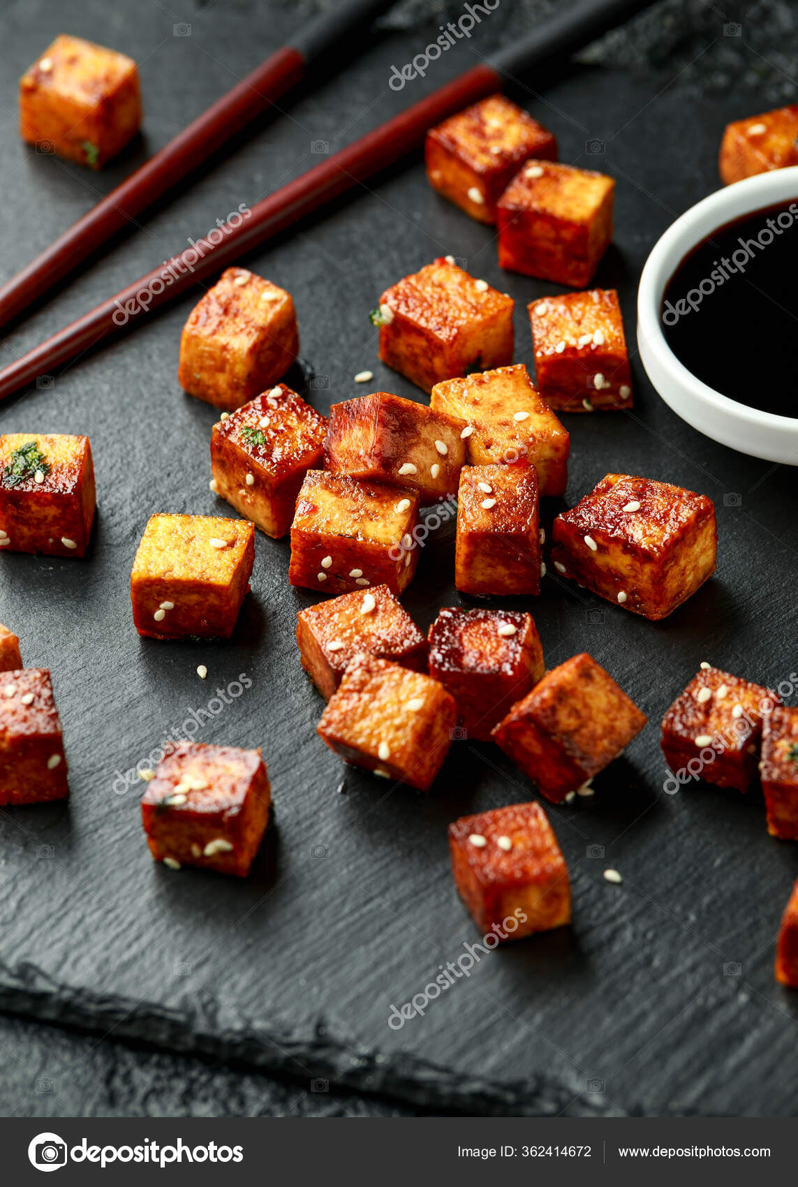 Gebratener Tofu mit Essstäbchen und Sesam auf rustikalem Steinbrett ...