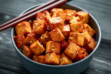 Çubuk ve susamlı kase içinde kızarmış tofu.