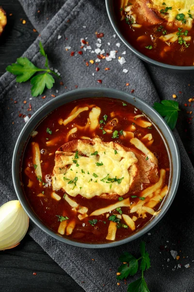 French onion soup with cheese toast on rustic background