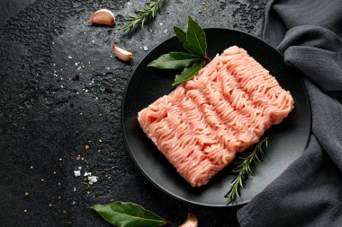 Çiğ hindi filetosu, kıymalı siyah tabakta pişmeye hazır et..