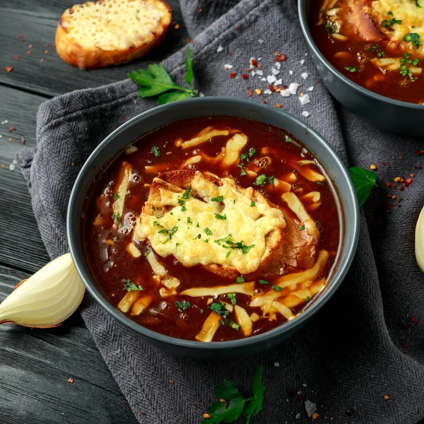 French onion soup with cheese toast on rustic background.