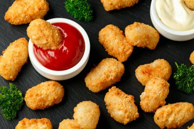 Çıtır çıtır karides nuggetları ketçaplı ve mayonezli rustik taş tahtada..