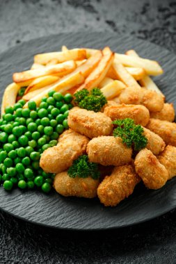 Patates cipsi ve yeşil bezelye ile servis edilmiş karides nuggetları.