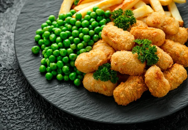 Nuggets crocantes de scampi batidos servidos em chapa de ardósia com batatas fritas e ervilhas verdes — Fotografia de Stock