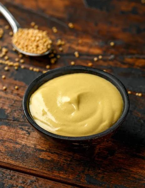 Dijon mustard in bowl on wooden table. Stock Photo