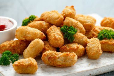 Beyaz tahta üzerinde ketçaplı çıtır çıtır karides nuggetları.