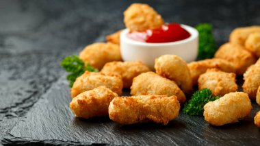 Çıtır çıtır karides nuggetları ketçaplı ve mayonezli rustik taş tahtada..