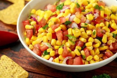 Limonlu ve ahşap masada tortilla cipsli Meksika Corn Salsa 'sı. Sağlıklı yemek.