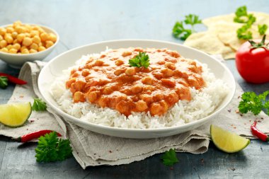 Acılı nohut körisi, pilav, domates ve beyaz tabakta Poppadom. Sağlıklı, lezzetli vejetaryen yemekleri.
