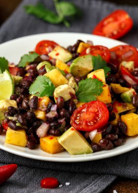 Avokado, beyaz tabakta siyah fasulyeli mango salatası