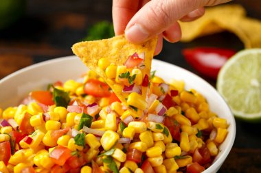 Limonlu ve ahşap masada tortilla cipsli Meksika Corn Salsa 'sı. Sağlıklı yemek.