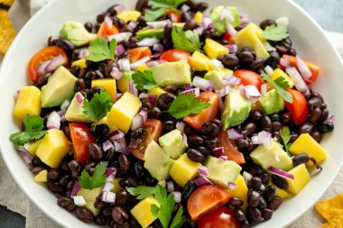 Avokado, siyah fasulyeli mango salatası, domates, kırmızı soğan ve tortilla cipsi. sağlıklı yiyecekler