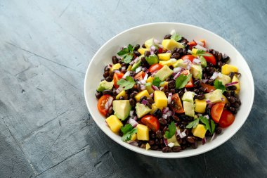 Avokado, siyah fasulyeli mango salatası, domates, kırmızı soğan ve tortilla cipsi. sağlıklı yiyecekler