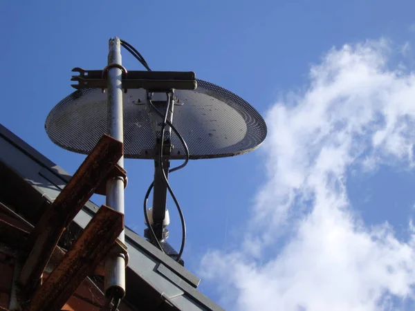 Une antenne de télévision avec un plat en maille contre un ciel bleu — Photo