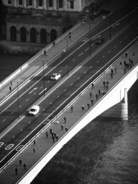 Una vista desde el puente de Londres en blanco y negro que muestra el tráfico temprano en la mañana y los peatones cruzando — Foto de Stock