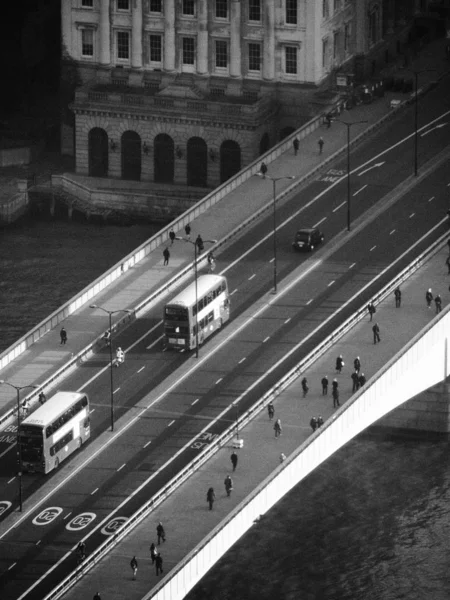 Una vista desde el puente de Londres en blanco y negro que muestra el tráfico temprano en la mañana y los peatones cruzando — Foto de Stock