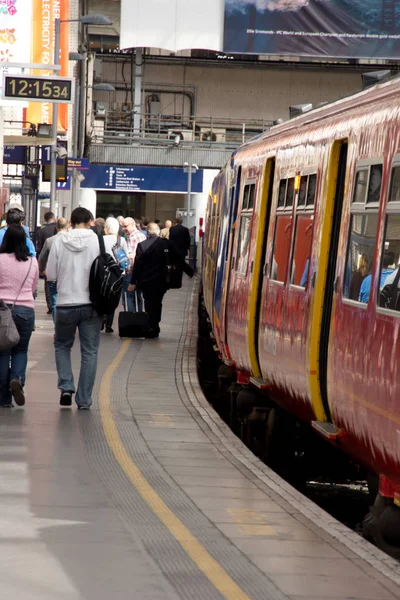Ein Pendlerzug am Bahnhof London Waterloo mit Fahrgästen, die am Bahnsteig entlang laufen — Stockfoto