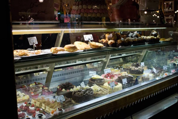 Illuminated shop display in an upmarket patisserie in London showing array of cakes and pies — Stock Photo, Image