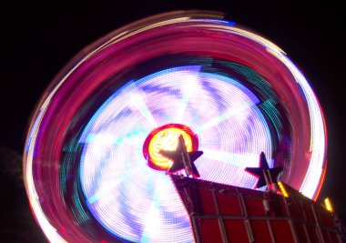 long exposure view of fairground ride at night with light trails and motion blur