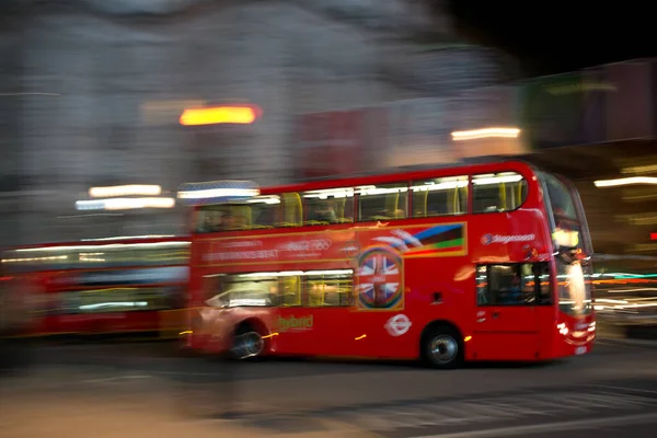 A red doubledeck London bus at night seen with motion blur against blurred lights — Stock Photo, Image