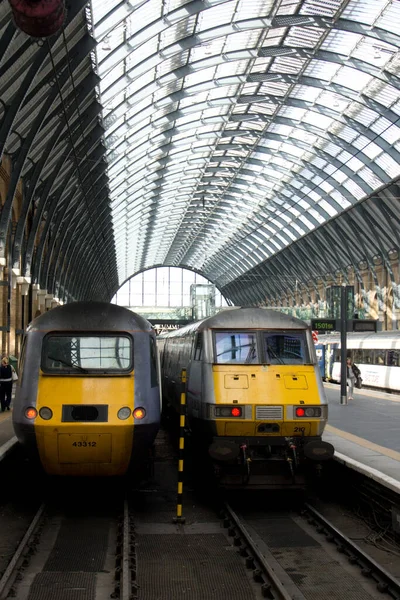 Zwei Züge am Bahnhof Kings Cross in London unter einem geschwungenen Stahldach — Stockfoto