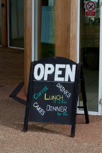 a cafe sign saying open for cakes, coffee ,lunch and drinks