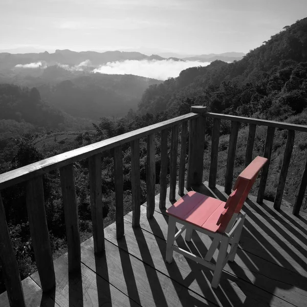 pink wooden chairs on terrace with misty mountain hills backgrou