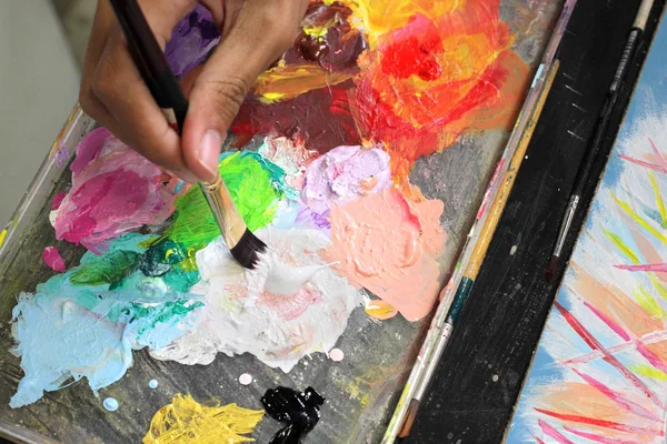 Artistes mélangeant les couleurs sur palette bois — Photo