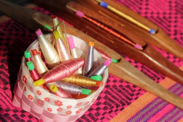 Bobinas coloridas en cesta y bobina de madera en tela de seda — Foto de Stock