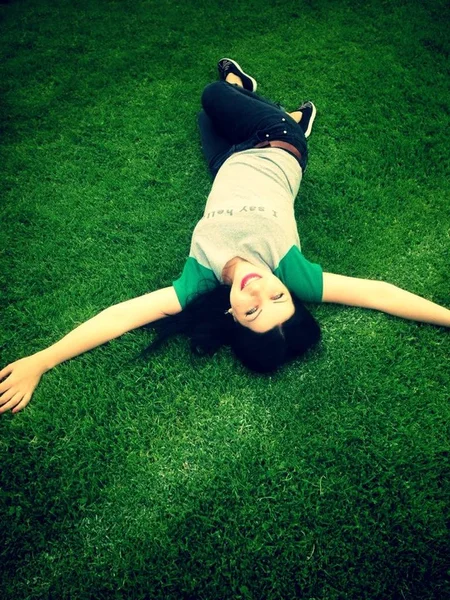少女は芝生の上に横になり笑顔で — ストック写真