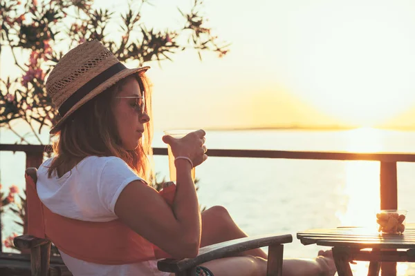 Young woman enjoying sunset at a beach bar — Stock Photo, Image