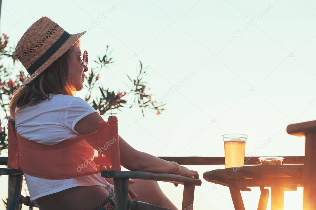 Young woman enjoying sunset at a beach bar