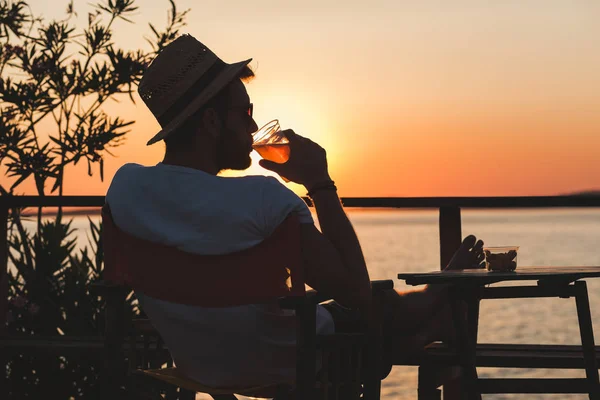 Молодий чоловік насолоджується заходом сонця в пляжному барі — стокове фото