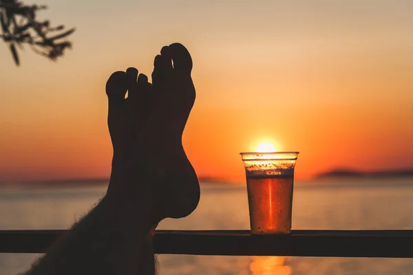 人間の足と夕日とビール一杯 — ストック写真