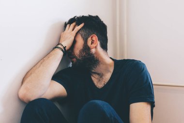 Odanın köşesinde oturan üzgün genç adam