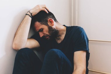 Odanın köşesinde oturan üzgün genç adam