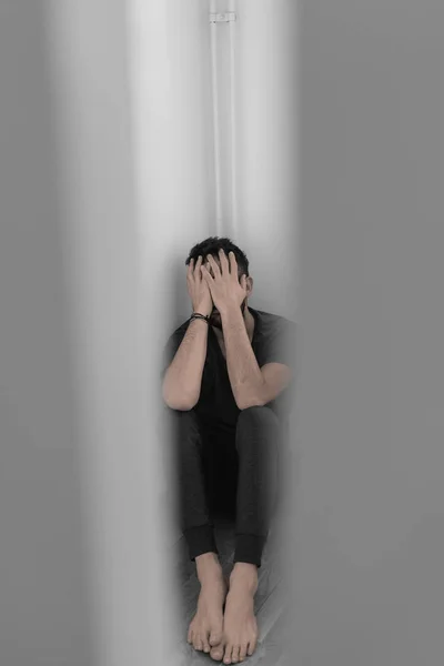 Young man in pain sitting in the empty room — Stock Photo, Image