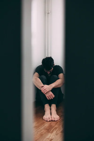 Young man in pain sitting in the empty room — Stock Photo, Image
