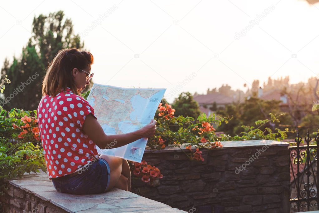 Young woman with the map at the balcony