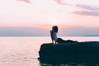 Deniz kenarında yoga yaparken genç bir kadın