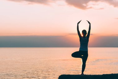 Deniz kenarında yoga yaparken genç bir kadın