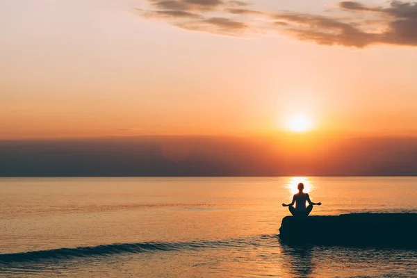 Deniz kenarında yoga yaparken genç bir kadın