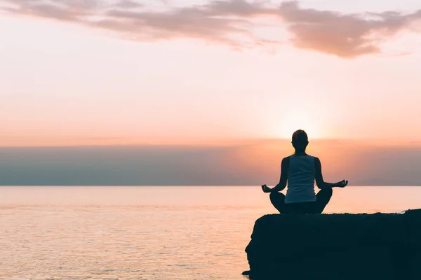 Mujer joven haciendo yoga junto al mar — Foto de Stock