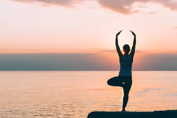 Mujer joven haciendo yoga junto al mar — Foto de Stock