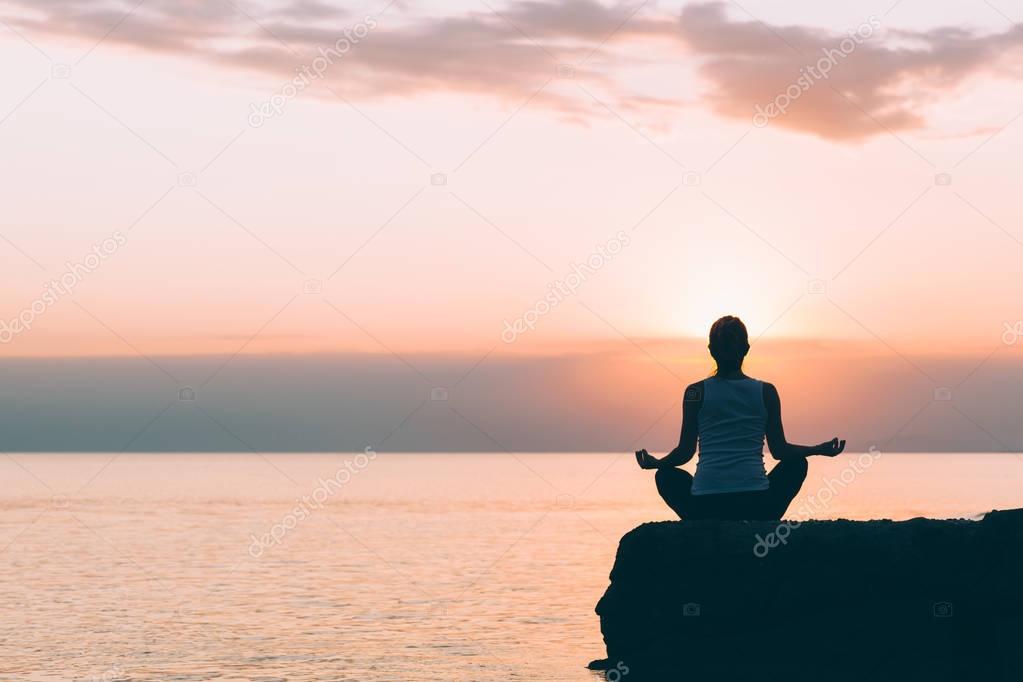 Young woman doing yoga by the sea