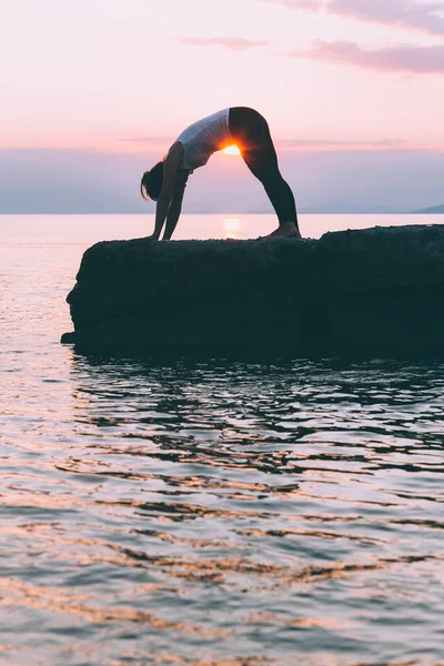 Deniz kenarında yoga yaparken genç bir kadın