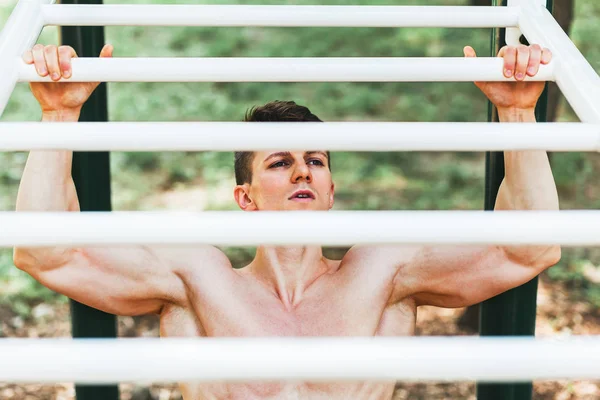 Muskulös ung man göra pull ups övningar på bar — Stockfoto